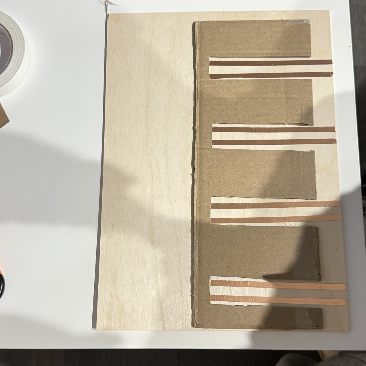 Cardboard and copper tape work as low-cost materials for testing alignment and electrical flow. The unknown is whether these materials will be durable enough once covered or used repeatedly by actual pets.