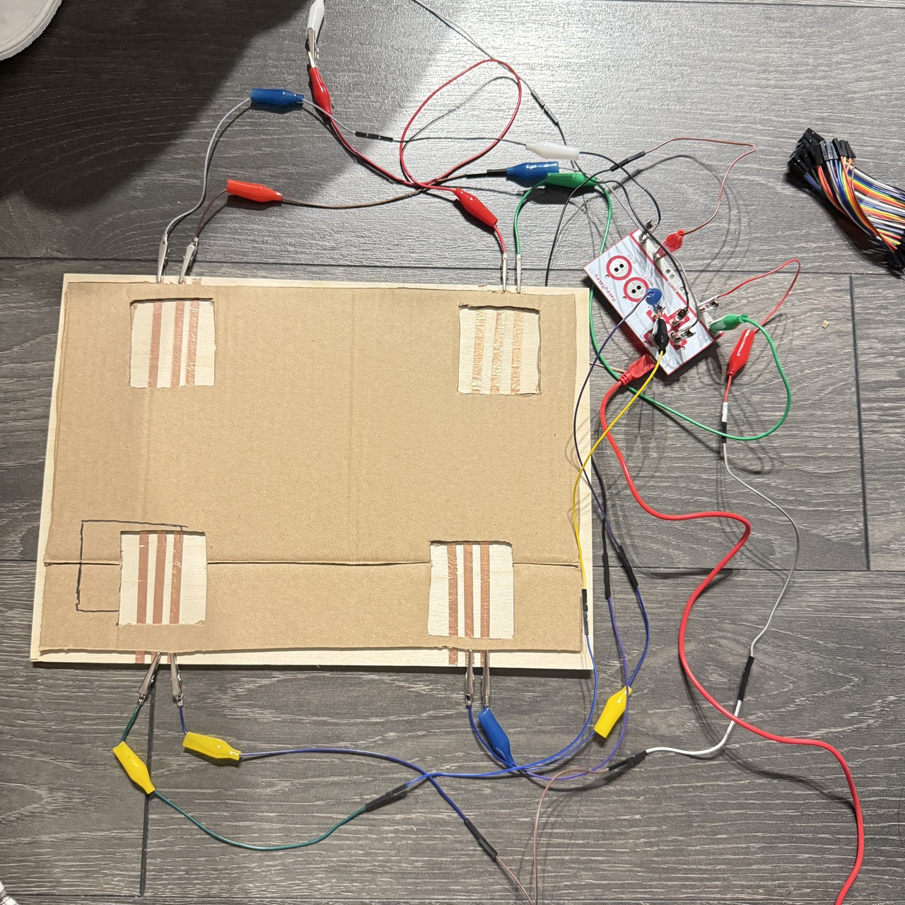 When all four pads are wired simultaneously, the prototype successfully detects multiple independent inputs. The challenge remains to prevent short-circuits and ensure the pads do not trigger accidentally when pressure spreads across the cardboard.
